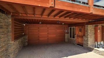Eine Garage mit einer großen Holztür, einer Steinmauer und einem Holzvordach.