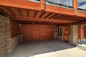 A garage with a large wooden door, a stone wall, and a wooden overhang.