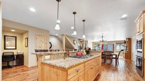 A spacious kitchen with a large island, wooden cabinets, and a dining area with a view.