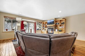 A living room with a fireplace, bookshelves, and a large window with a view.
