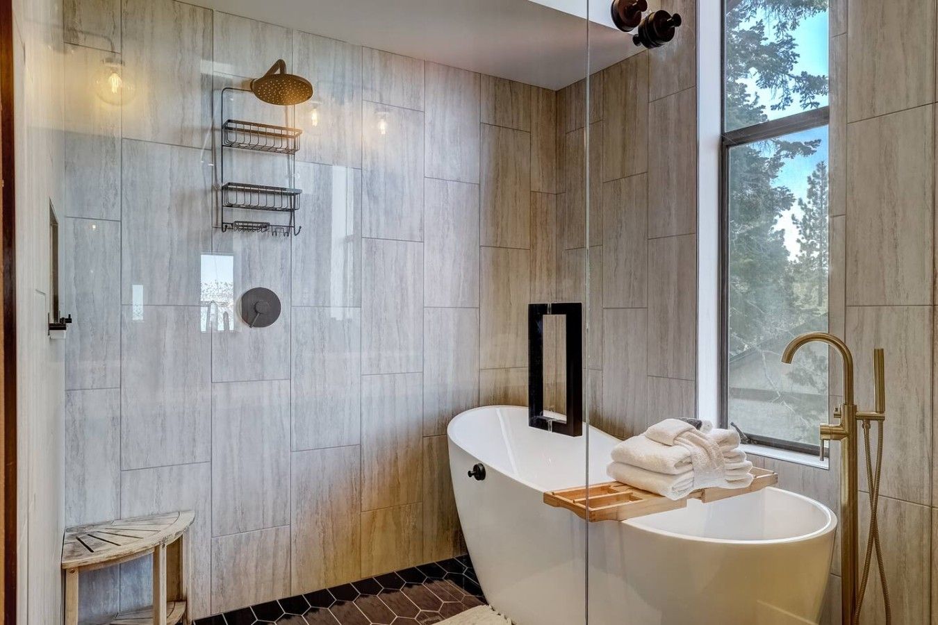 Une salle de bain moderne avec une baignoire sur pieds, un espace douche et une fenêtre donnant sur les arbres.