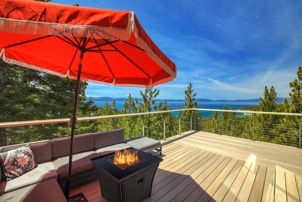 A deck with a fire pit, outdoor seating, and a red umbrella.