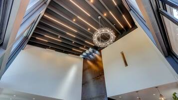 A modern interior with a high ceiling, a central column, and a chandelier.