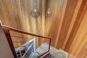 A staircase with a wooden wall and metal railing, leading to an upper floor.