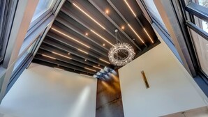 A modern interior with a high ceiling, a central column, and a chandelier. - Luxury Estate | Hot Tub & Lake Views | Sleeps 8 (Glenbrook)