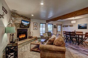A living room with a fireplace, a couch, a dining table, and a view of the outdoors. - Cozy Condo | Near Heavenly-Fireplace | Sleeps 6 (Stateline)
