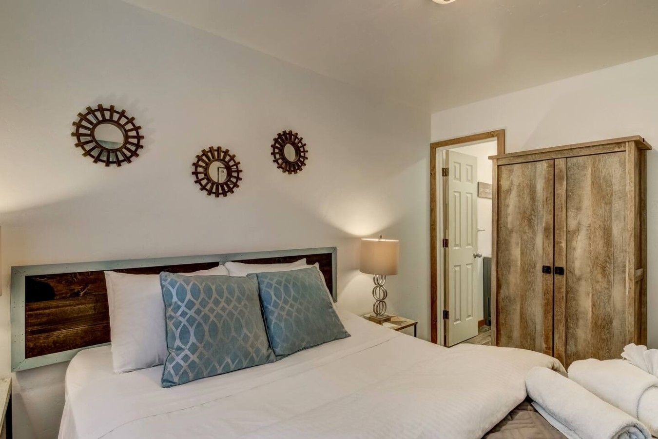 Een hotelkamer met een bed, twee spiegelwanden, een bedlampje en een kledingkast.