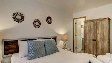 Een hotelkamer met een bed, twee spiegelwanden, een bedlampje en een kledingkast.
