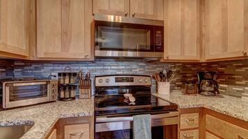 A kitchen with wooden cabinets, a microwave, a toaster oven, and a stove.