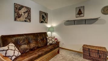 Een woonkamer met een bruine leren bank, een groene vloerlamp en een rieten dressoir.
