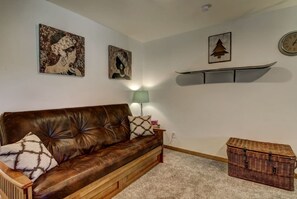 A living room with a brown leather sofa, a green floor lamp, and a wicker chest of drawers. - Cozy Condo | Near Heavenly-Fireplace | Sleeps 6 (Stateline)