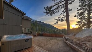 Un bain à remous sur une terrasse en bois, avec une vue sur les montagnes en arrière-plan.