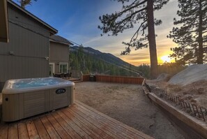 Un bain à remous sur une terrasse en bois, avec une vue sur les montagnes en arrière-plan.