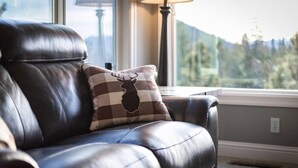 Un canapé en cuir agrémenté d’un coussin à carreaux orné d’un motif représentant la tête d’un cerf.