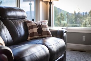 Un canapé en cuir agrémenté d’un coussin à carreaux orné d’un motif représentant la tête d’un cerf.