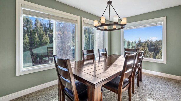 Une salle à manger avec une grande table, six chaises et un lustre.