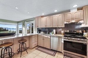 Una cocina moderna con electrodomésticos de acero inoxidable, armarios de madera y un amplio ventanal con vistas al exterior.
