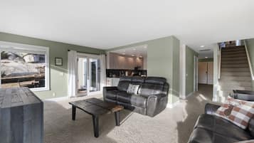 A living room with a sofa, a coffee table, and a view of a kitchen and a staircase.