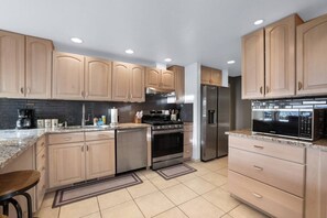 A modern kitchen with wooden cabinets, stainless steel appliances, and a granite countertop. - Luxury 4BR | BBQ, Hot Tub & Lake Views | Sleeps 8 (Glenbrook)