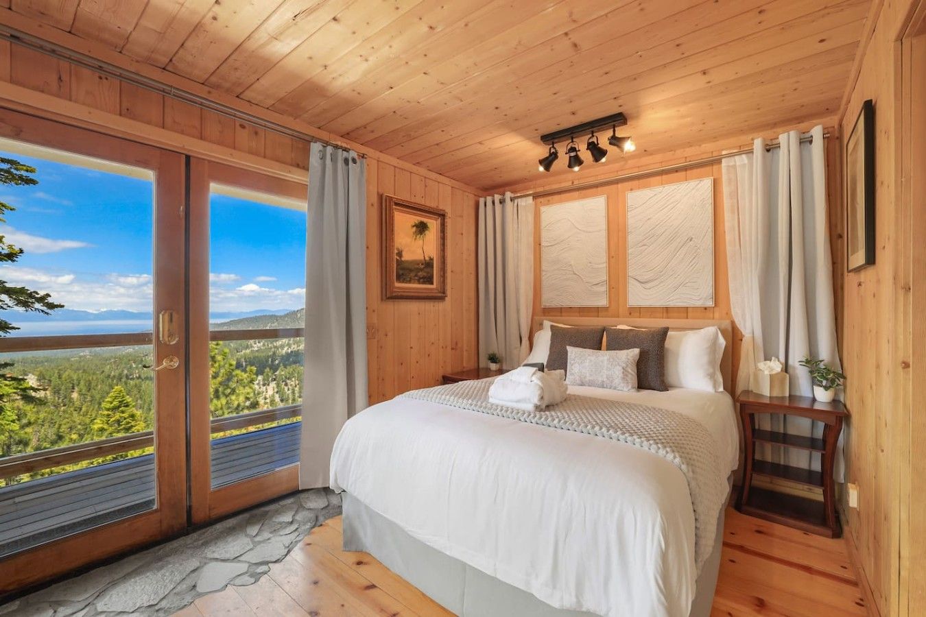 Un dormitorio con una cama grande, vistas al exterior y paredes de madera.