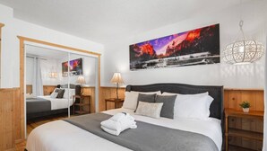 A hotel room with a large bed, two bedside tables, a mirror, and a painting on the wall. - Heavenly Escape | Lake Views, Pets OK | Sleeps 6 (Stateline)