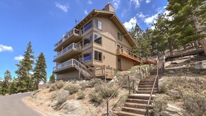 A multi-story building with balconies, a staircase leading up to the entrance, and a surrounding natural landscape. - Heavenly Escape | Lake Views, Pets OK | Sleeps 6 (Stateline)
