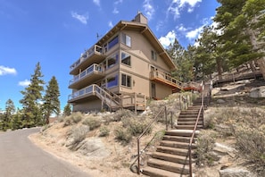 A multi-story building with balconies, a staircase leading up to the entrance, and a surrounding natural landscape. - Heavenly Escape | Lake Views, Pets OK | Sleeps 6 (Stateline)