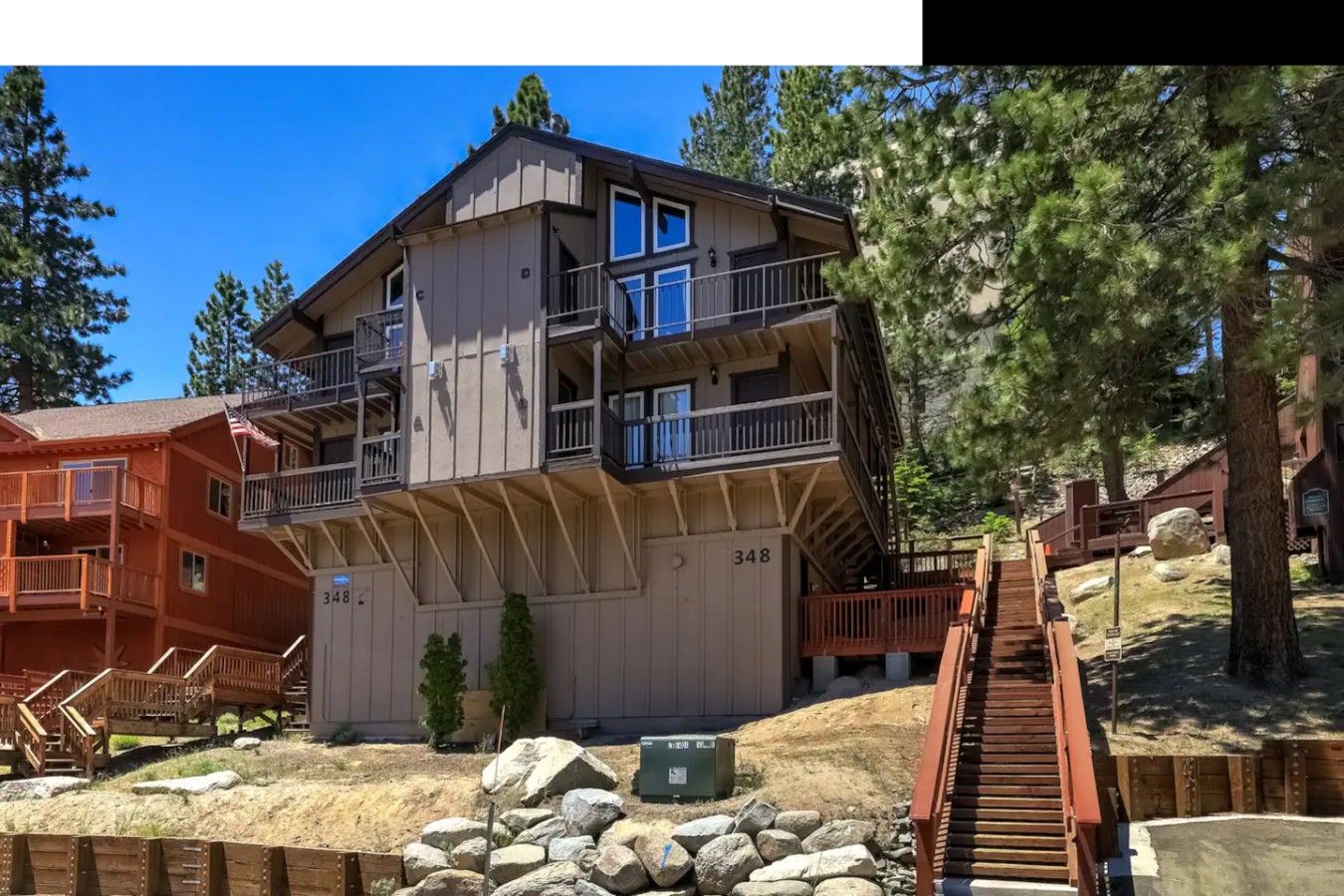 A multi-story building with balconies, a staircase, and a surrounding natural landscape.