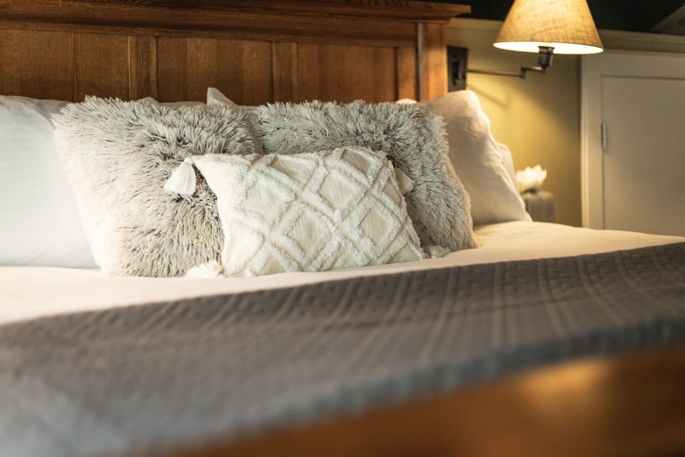 A bed with fluffy pillows and a textured blanket.