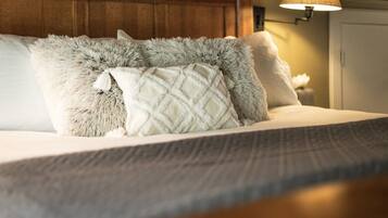 A bed with fluffy pillows and a textured blanket.