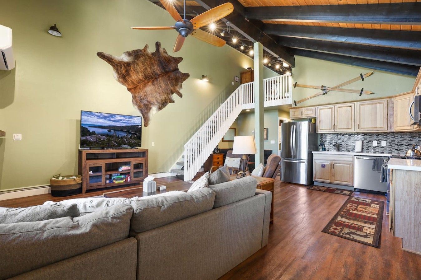 A spacious living room with a large sofa, a flat-screen TV, and a unique wall-mounted animal hide.