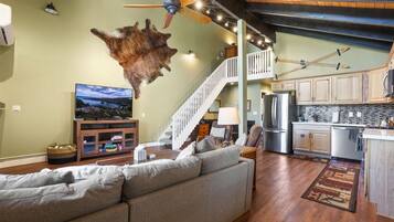A spacious living room with a large sofa, a flat-screen TV, and a unique wall-mounted animal hide.