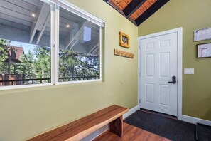 Una habitación con un banco, una puerta y una ventana con vistas a árboles.