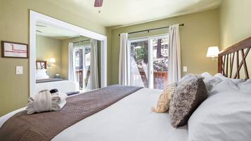 A hotel room with a large bed, a ceiling fan, a window with curtains, and a view of the outdoors.