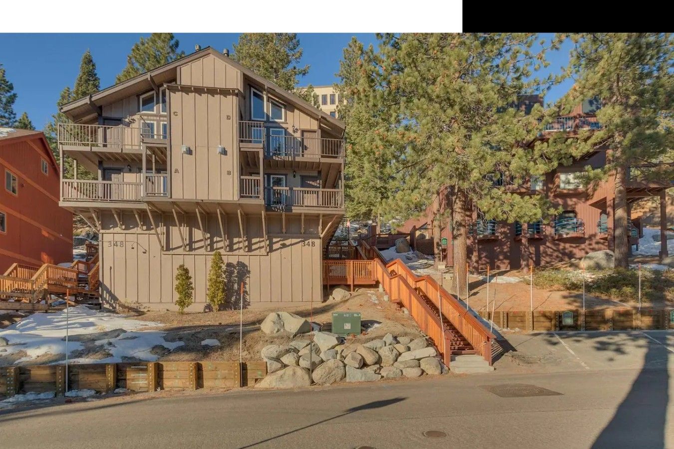 A multi-story building with balconies, a staircase, and a view of trees.