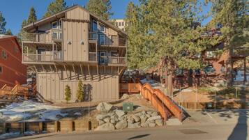 A multi-story building with balconies, a staircase, and a view of trees.