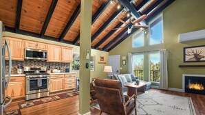 A spacious living area with a fireplace, a dining table with chairs, and a large window providing a view of the outdoors. - Ski-In Heavenly Condo | Cozy 3BR | Sleeps 8 (Stateline)
