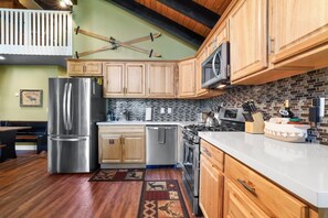 A kitchen with wooden cabinets, stainless steel appliances, a microwave, and a tiled backsplash. - Ski-In Heavenly Condo | Cozy 3BR | Sleeps 8 (Stateline)