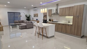 A modern kitchen with a central island, wooden cabinets, and stainless steel appliances. - Carousel - Modern Spacious Apartment  (Qrendi)