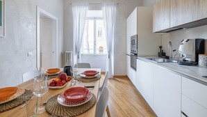 A modern kitchen with white cabinets, a built-in oven, and a large window with white curtains. - Angela Luxury Home, Families Premium Apartment (Roma)