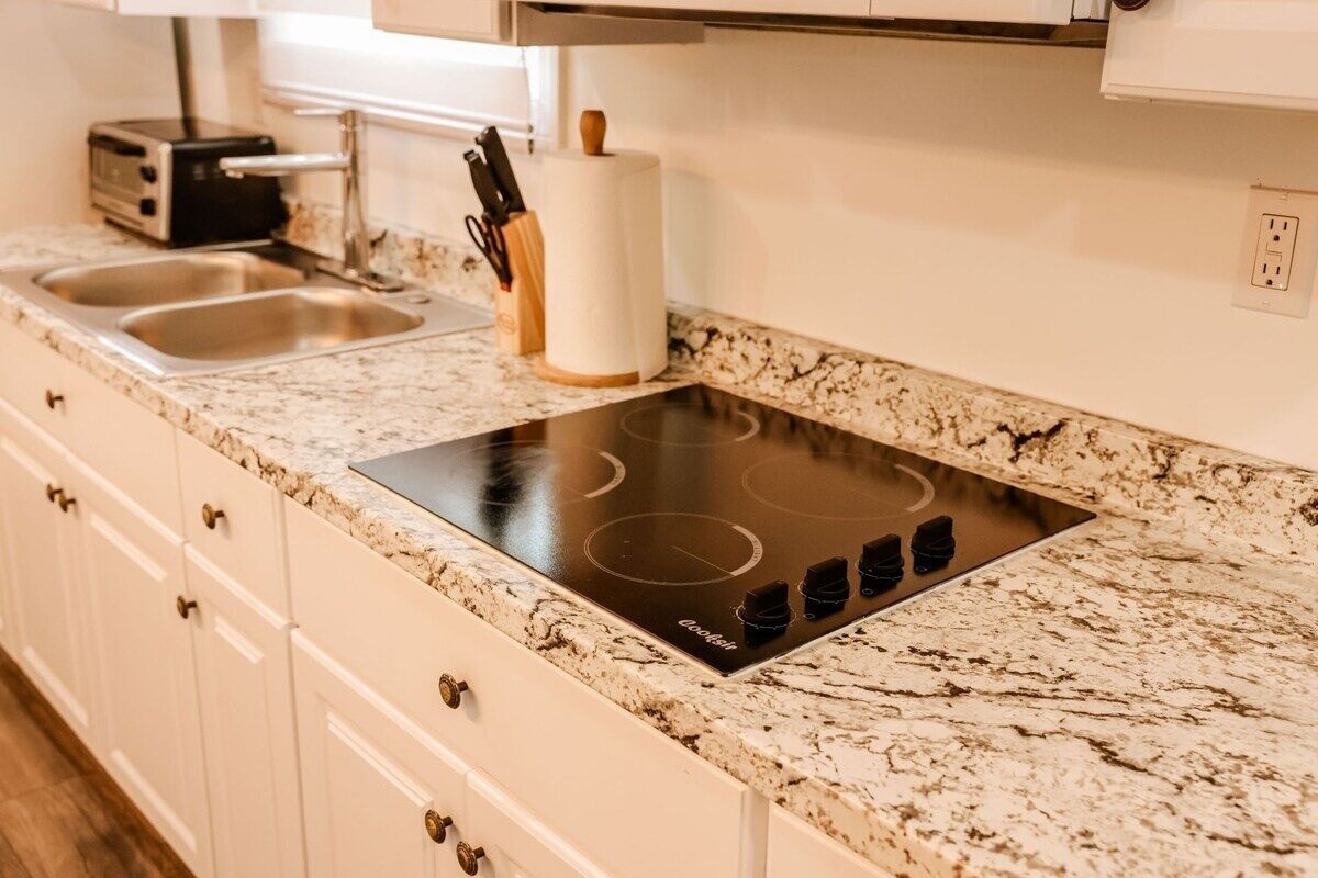 A kitchen with a built-in induction cooktop, a toaster, and a paper towel holder.