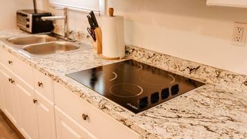 A kitchen with a built-in induction cooktop, a toaster, and a paper towel holder.