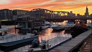 A marina with boats docked, a bridge in the background, and a city skyline. - By D&D Vacation Rental (Providence)
