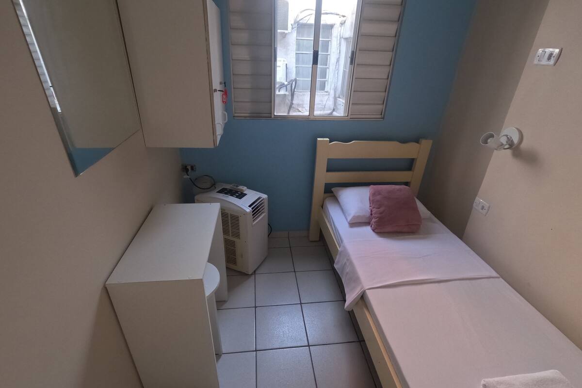 A small, compact room with a bed, a desk, and a window.