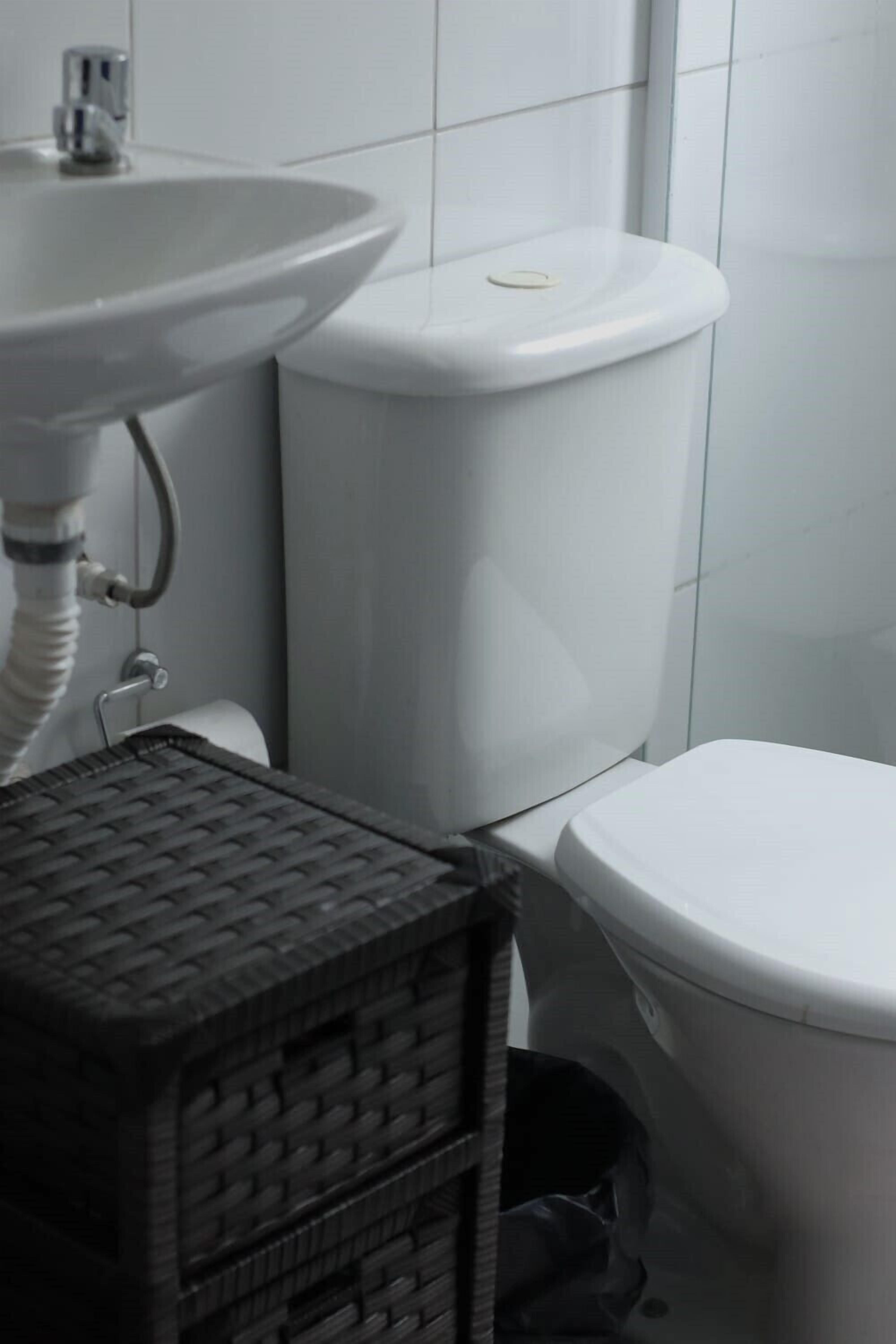 Een badkamer met een wit wastafel, toilet en een kleine prullenbak.
