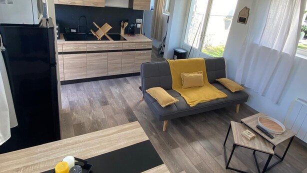 A modern living space with a kitchen, dining area, and a sofa. - Maisonnette T2 (Saint-André-les-Vergers)