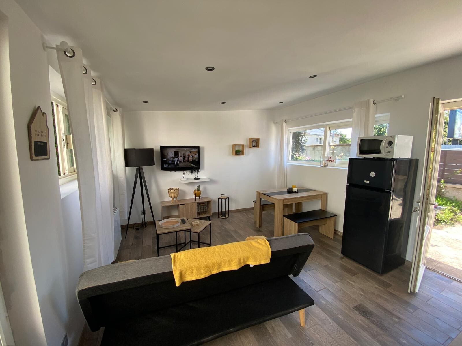 Un espacio habitable compacto con sofá, mesa de comedor, televisor y refrigerador.