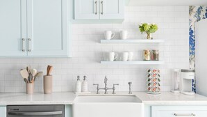 A modern kitchen with light blue cabinets, white countertops, and a stainless steel dishwasher.