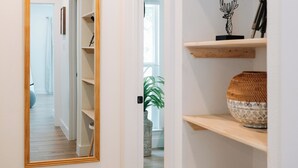 Un pasillo con un espejo grande, estanterías de madera y una planta.
