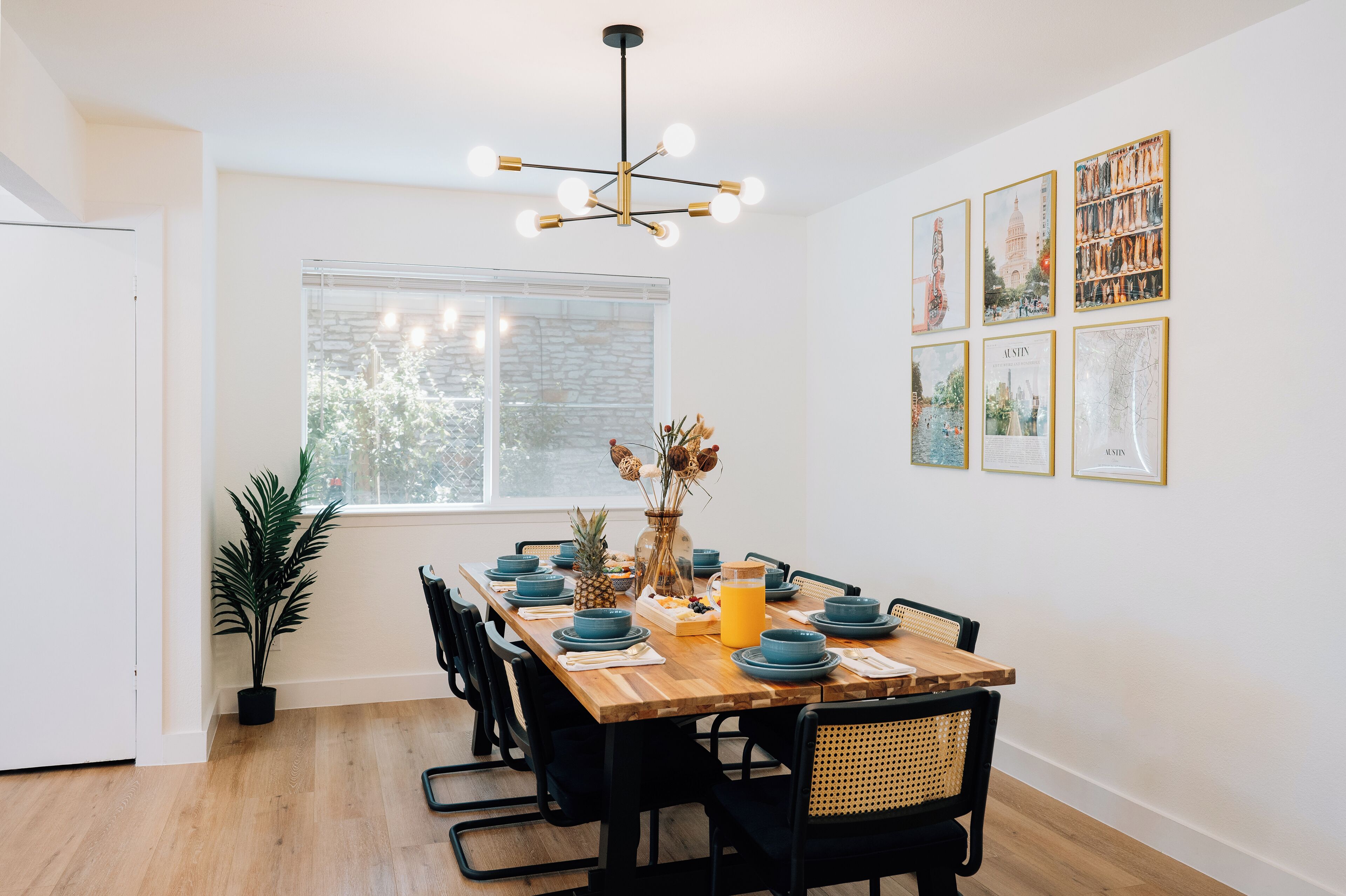 A dining area with a wooden table, black chairs, and a modern chandelier.